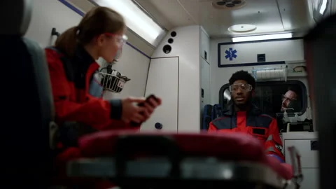 Paramedics driving on accident in emergency car. Team talking in ambulance van Stock Footage 166876341