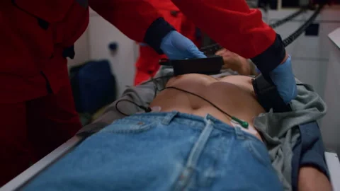 Paramedics hands making cpr with defibrillator on man in emergency car Stock Footage 166865582