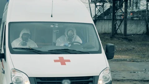 Paramedics in hazmat suits are driving an ambulance Video stock 128987341