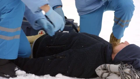 Paramedics Inspecting Man Lying on Snow Stock Footage 123689159
