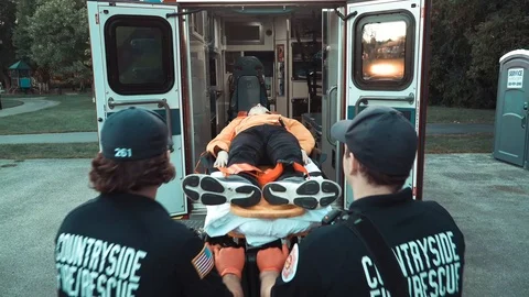 Paramedics loading dummy on stretcher into ambulance. Rear view. Stock Footage 120194580
