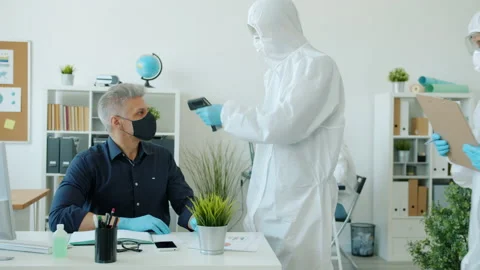 Paramedics in protective costumes testing body temperature of office workers Stock-Footage 131278437