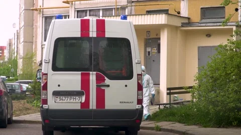 Paramedics in protective suits sit in an emergency car.  動画素材 130529006