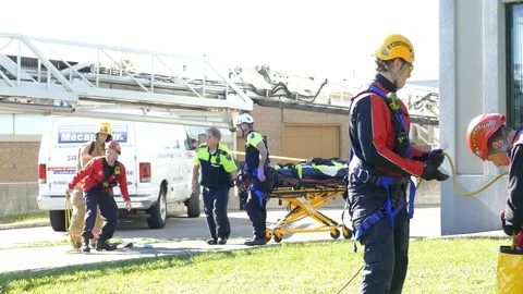 Paramedics pull stretcher with work accident victim under firetruck's ladder Video stock 95913155