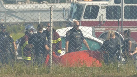Paramedics putting down a tarp onto body of fatal car crash victim Video stock 114683372