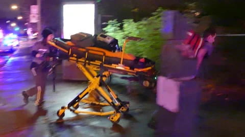 Paramedics running with stretcher towards crime scene and under yellow tape Stock Footage 43312288