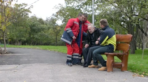 Paramedics rushing to help the old Man with a Heart Attack - Day in City Park Stock Footage 68743803