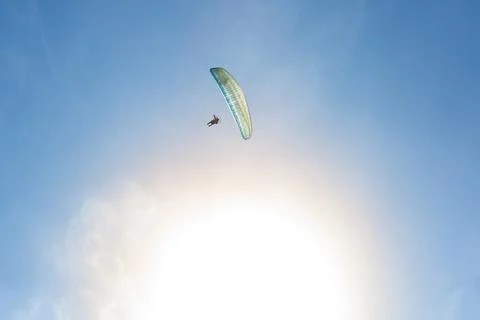Paramotor flying alone with the sun in the background Stock Photos