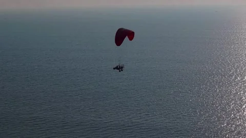 Paramotor Flying Over a Tropical Beach at Sunset 動画素材 324030770