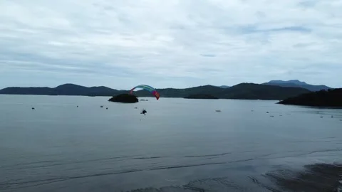 Paramotor glider turn and fly along the Jabaquara Beach in Paraty, Brazil 動画素材 328349677