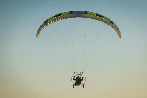 Paramotor pilot flying with a green powered paraglider in the clear sky dur.. Stock Photos