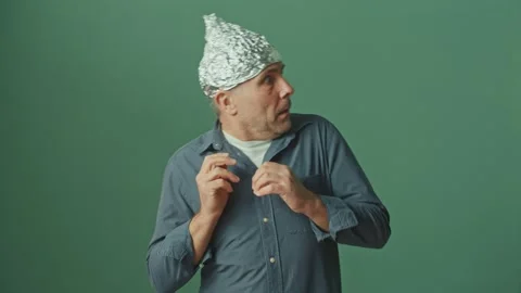 A Paranoid Man with a Protective Foil Cap on his Head Looks Around Anxiously Stock Footage 166652563