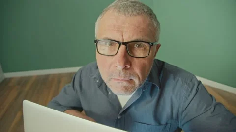 A Paranoid Man in a Protective Foil Cap Working on a Laptop Anxiously Peering Up Stock Footage 166705923