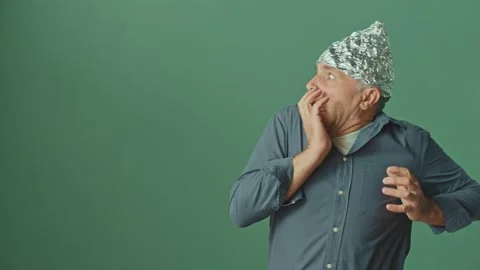 A Paranoid Man with a Protective Foil Cap on his Head Looks Around Anxiously Stock-Footage 166706536