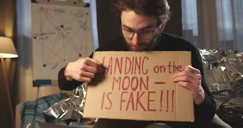 A paranoid, a supporter of pseudoscience holds a sign with a conspiracy slogan. Stock-Footage 272253252