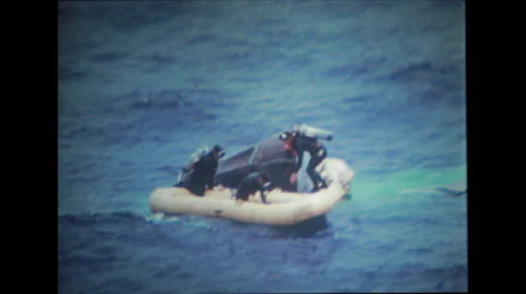 Pararescue divers attaching and securing collar and climbing on floating boat Stock-Footage 37596678