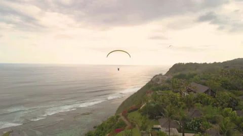 Parasail paraglide at sunset over cliffs and Luxury Villas Bali Stock Footage 136112084