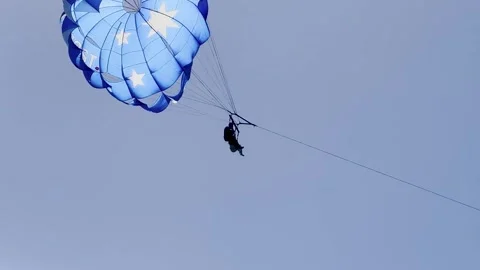 Parasailing Adventure with Blue Star Pattern Parachute Over Coastal Waters Stock Footage 326093920