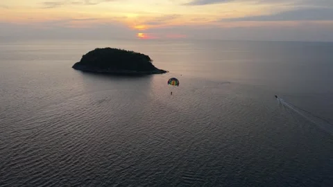 Parasailing adventure over tranquil ocean waters at sunset near island Vídeos de archivo 342331594