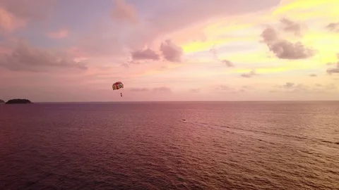 Parasailing kite soar over calm dark sea, bright afterglow on sunset sky Stockbeeldmateriaal 80450975