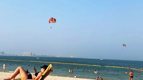 Parasailing over the beach during the day, people relaxing on the beach. High qu Stock Footage 253101109