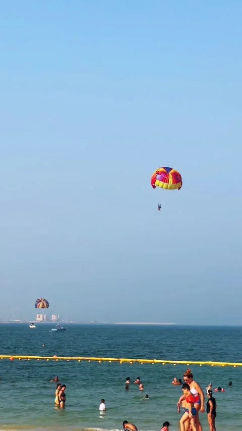 Parasailing over the beach during the day, people relaxing on the beach. High qu Stock Footage 253101110