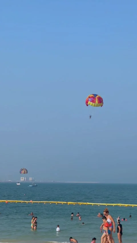 Parasailing over the beach during the day, people relaxing on the beach. High qu Stock Footage 253101111