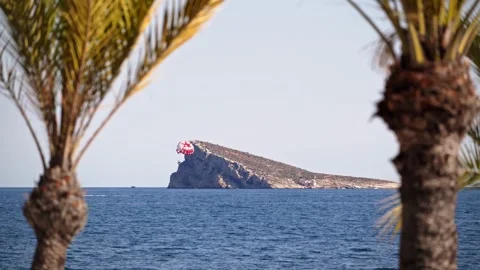Parasailing over sparkling blue ocean water near rocky island with palm tre.. Vídeos de archivo 339763953