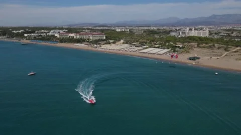 Parasailing pulled by speedboat leaves the beach Stock Footage 164362306