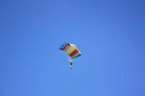 Parasailing, a skydiver flying against a blue sky. Stock Photos