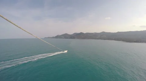 Parasailing While Flying Over Boat and Tropical Sea at Sunset Sky Stockbeeldmateriaal 65734465