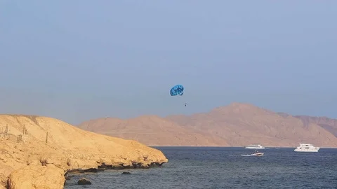 Parasailing. Yacht with a parachute sails along the island (mountains). Video stock 107656853