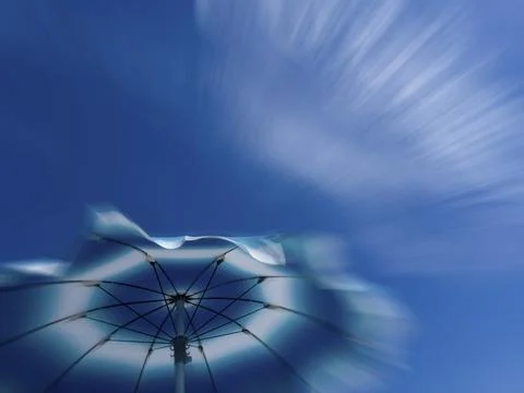 Parasol in front of a blue sky with clouds, zoom effect Stock Photos