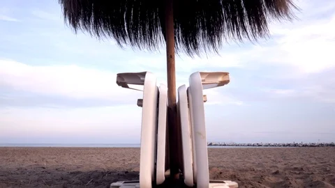 Parasol opened, and deckchairs folded on an empty sandy beach. Stock Footage 118852831