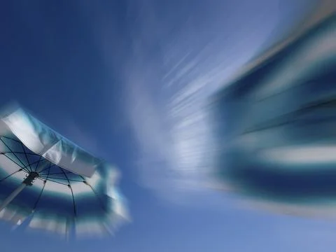 Parasols in front of a blue sky with clouds, zoom effect Stock Photos