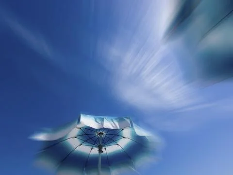 Parasols in front of a blue sky with clouds, zoom effect Stock Photos