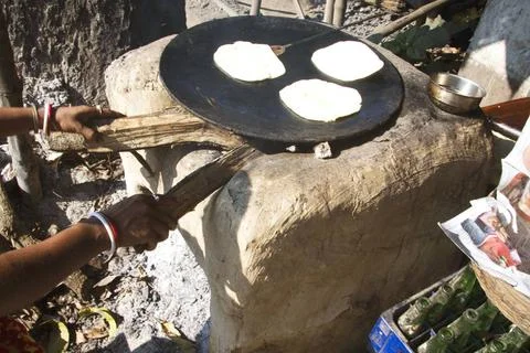 Paratha baking on round iron surface below firewood pushed chulli ; West B... 写真素材