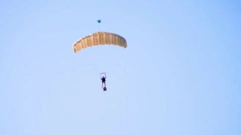 Paratrooper descends gracefully with a parachute under clear blue sky, Stock Footage 286295071