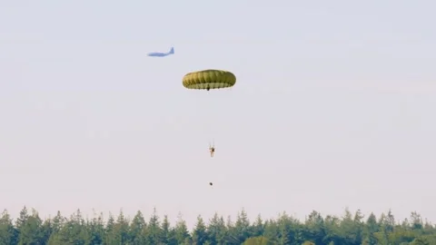 Paratrooper descends toward the ground with an open parachute during a Stock Footage 286424641