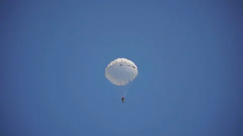 Paratrooper landed on the grass and meet his friends, blue sky, white parachute Stock Footage