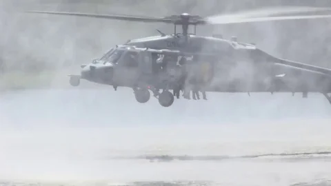 Paratroopers jump from a low flying helicopter into a lake. Stock Footage