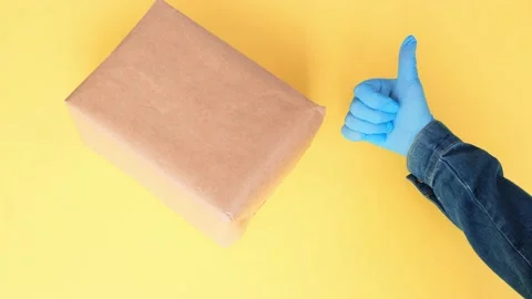 Parcel and courier's hands in protective glove showing thumbs up. 動画素材 130634475