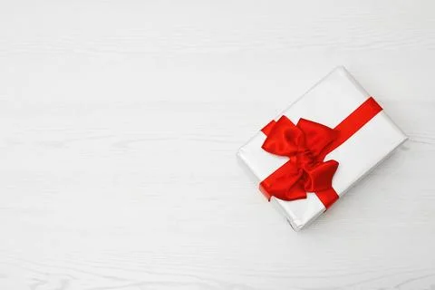 Parcel box with red bow and space for text on wooden background, top view Stock Photos