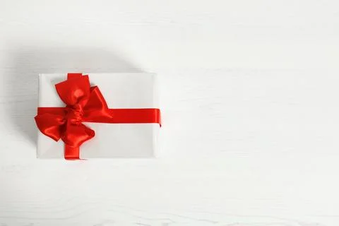 Parcel box with red bow and space for text on wooden background, top view Stock Photos