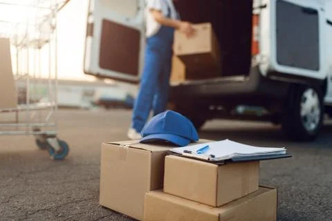 Parcel boxes and cap, deliveryman on background 스톡 사진