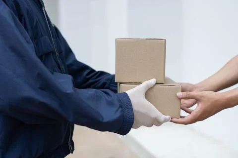 Parcel delivery concept the postman in white rubber gloves and light weight d Stock Photos