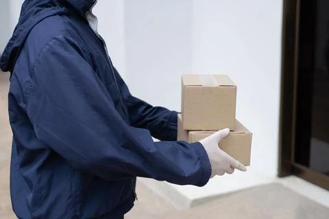 Parcel delivery concept the postman in white rubber gloves and light weight d Stock Photos