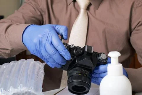 Parcel delivery during self-isolation. A man in rubber gloves takes a camera  写真素材