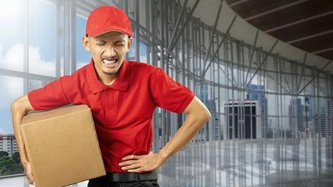 A parcel delivery man with a hat feels a stomachache while carrying a package Fotos de archivo