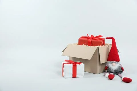 Parcel with gift boxes and decorative dwarf on light background Foto stock